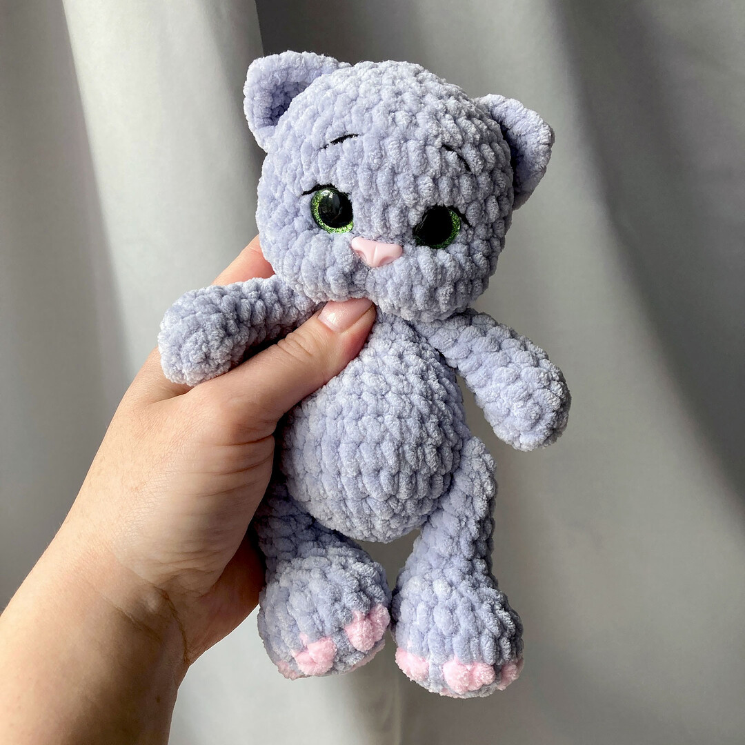 A finished amigurumi crochet kitten toy, gray with white accents, sitting down.